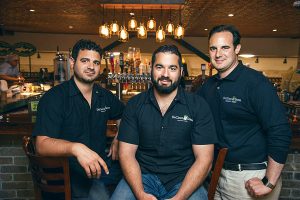 left to right: Chris DeCicco, Joseph DeCicco Jr., and John DeCicco Jr. in front of their Craft Beer Bar in Millwood